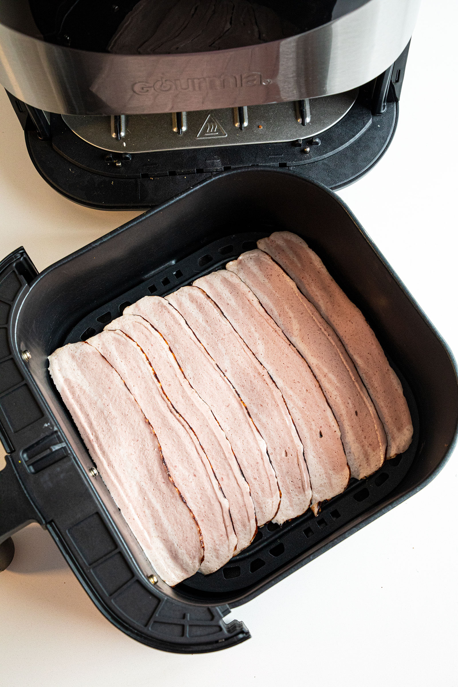 raw turkey bacon in layers in air fryer basket