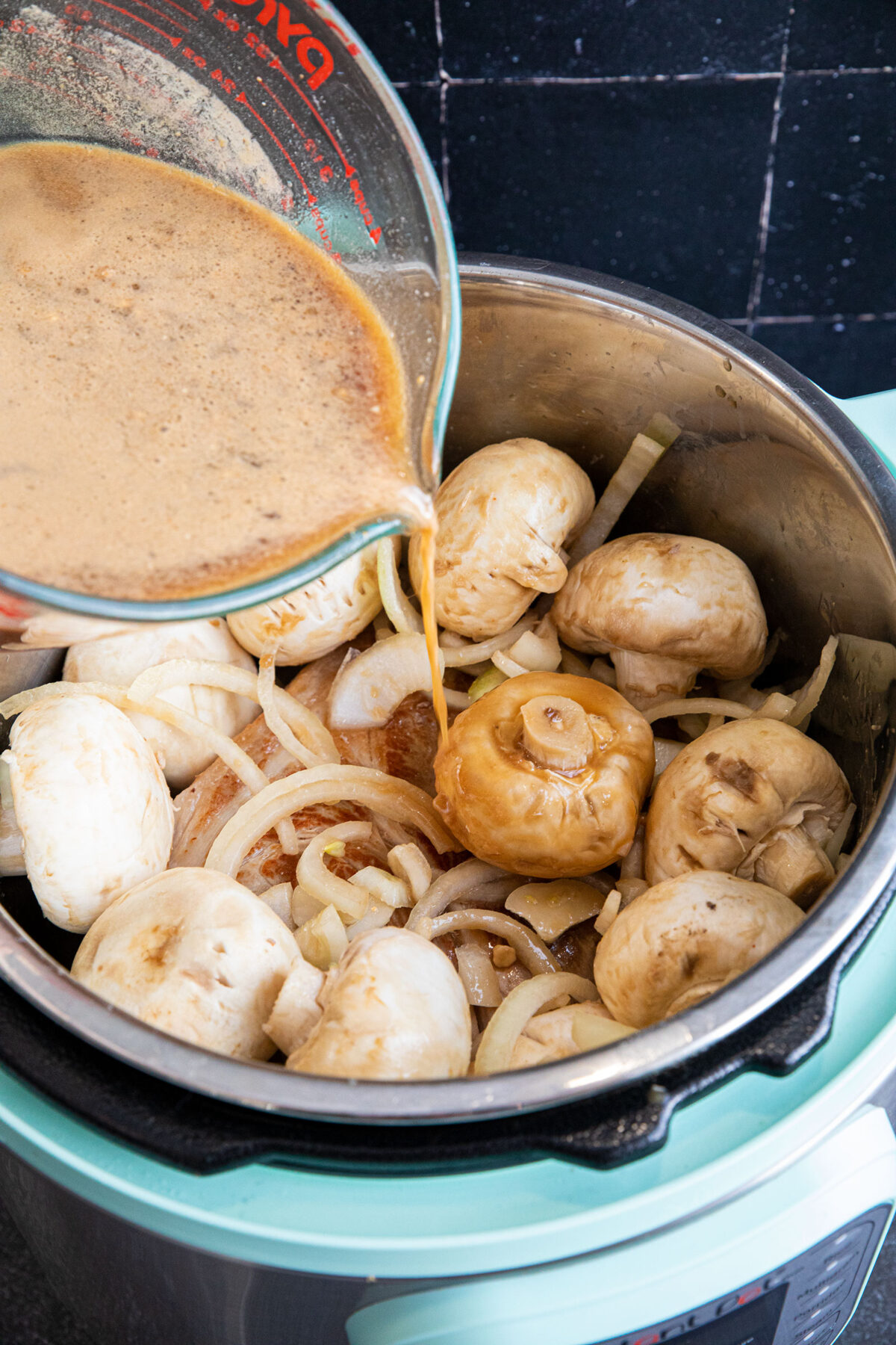 pouring gravy ingredients on raw pork butt roast