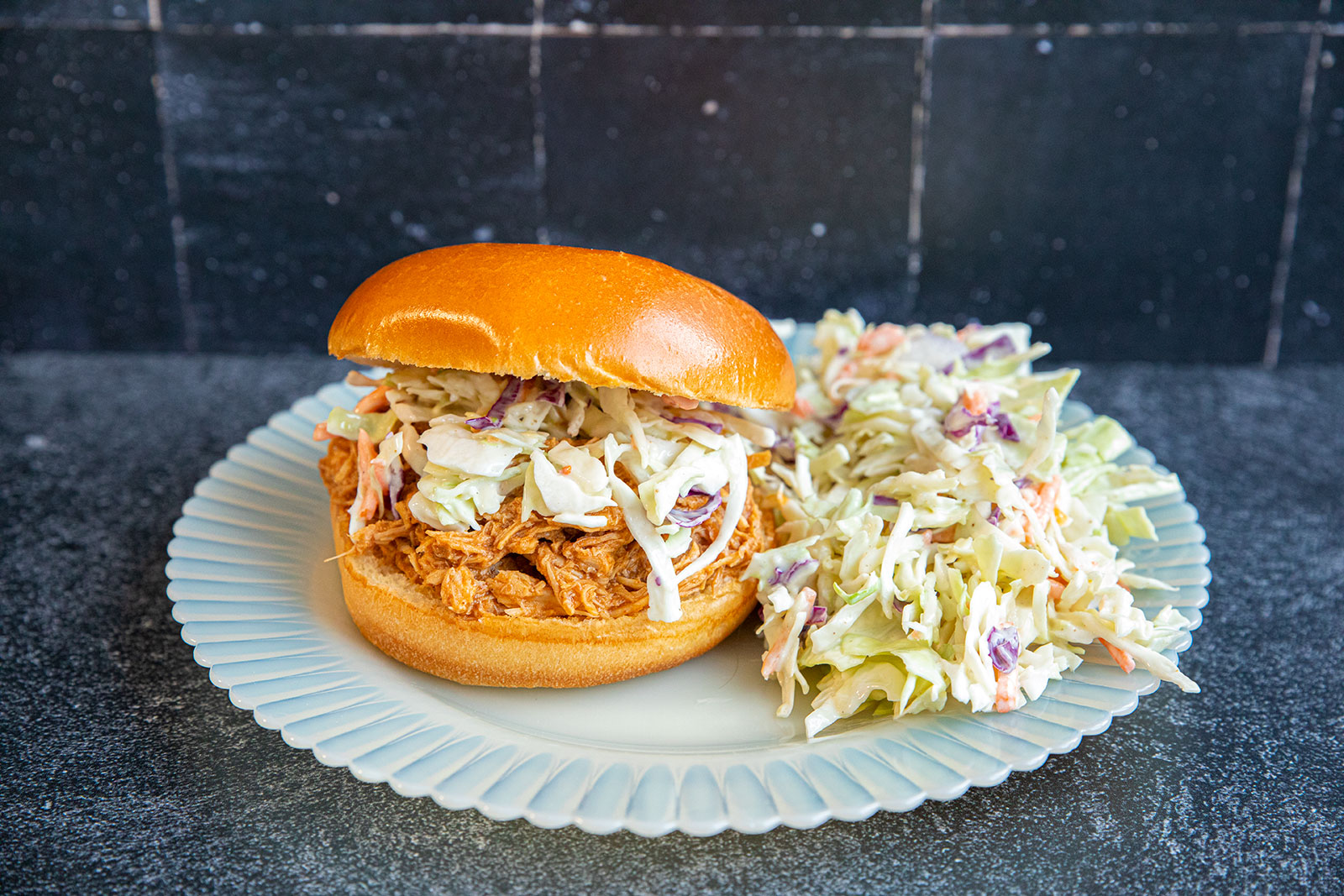 slow cooker pulled pork on a plate with a side of coleslaw