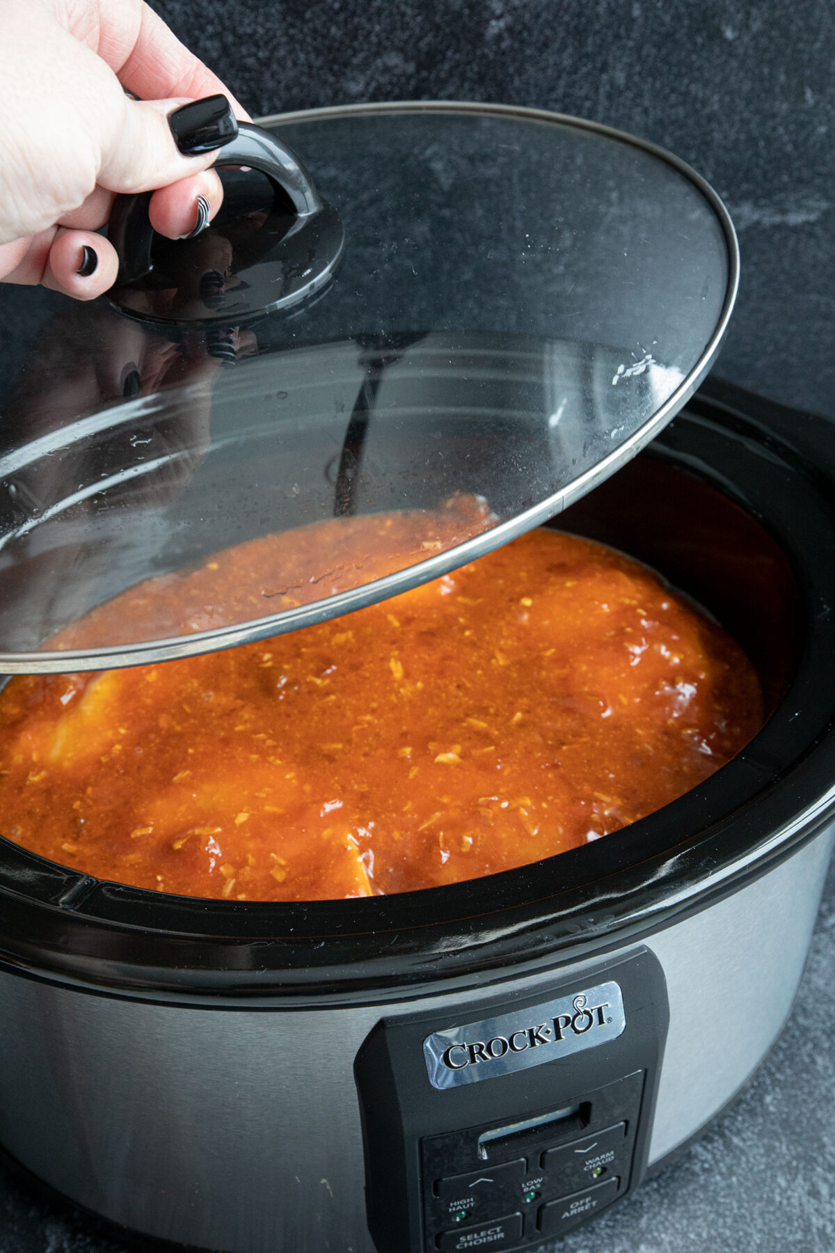 placing the slow cooker lid on the apricot chicken 