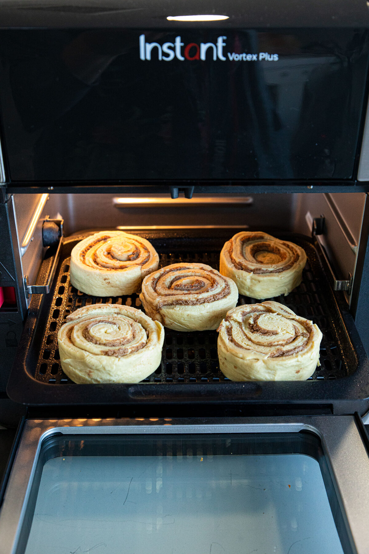 cinnamon roll dough on an air fryer baking rack