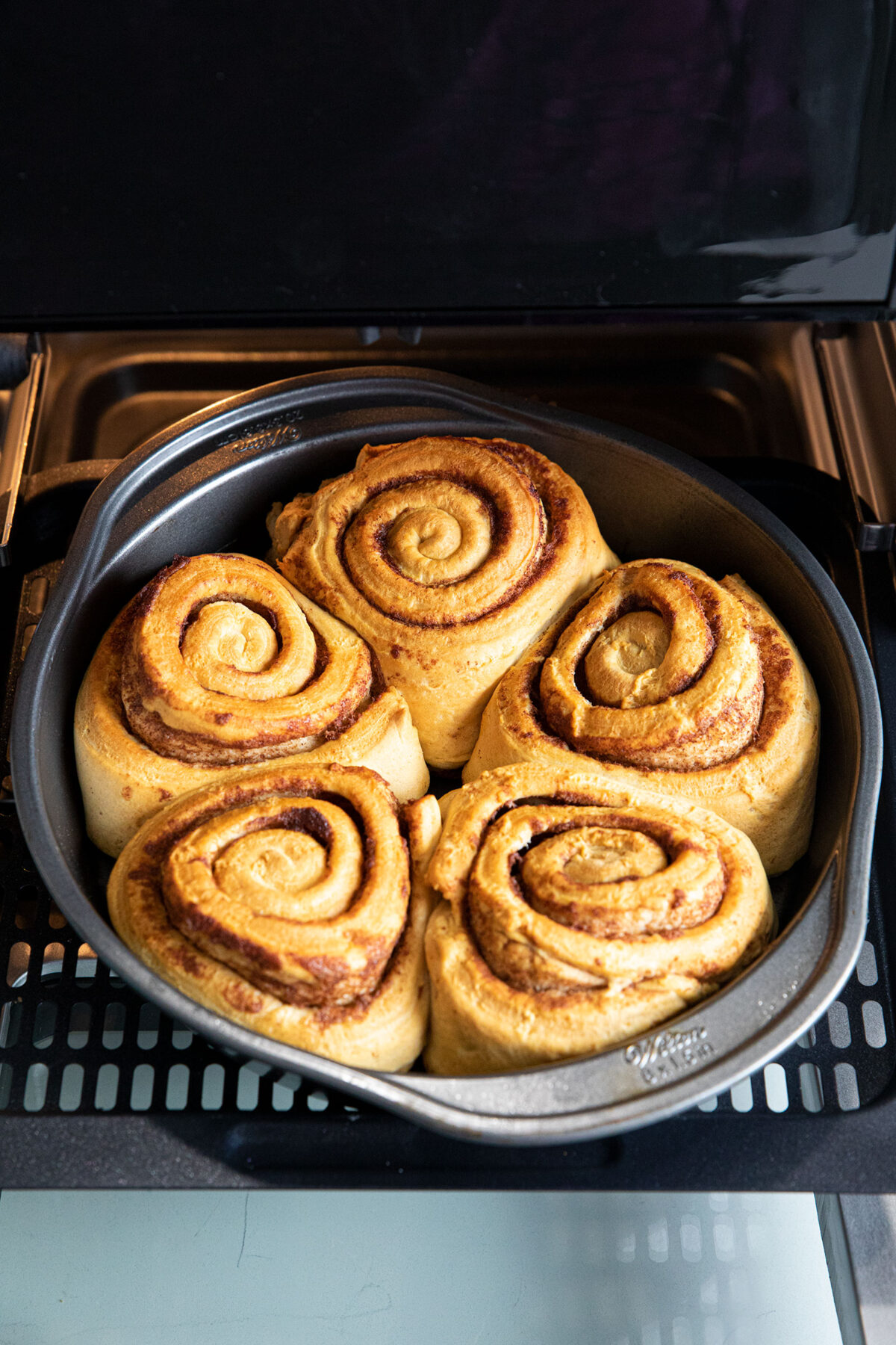baked cinnamon rolls in a pan in an air fryer