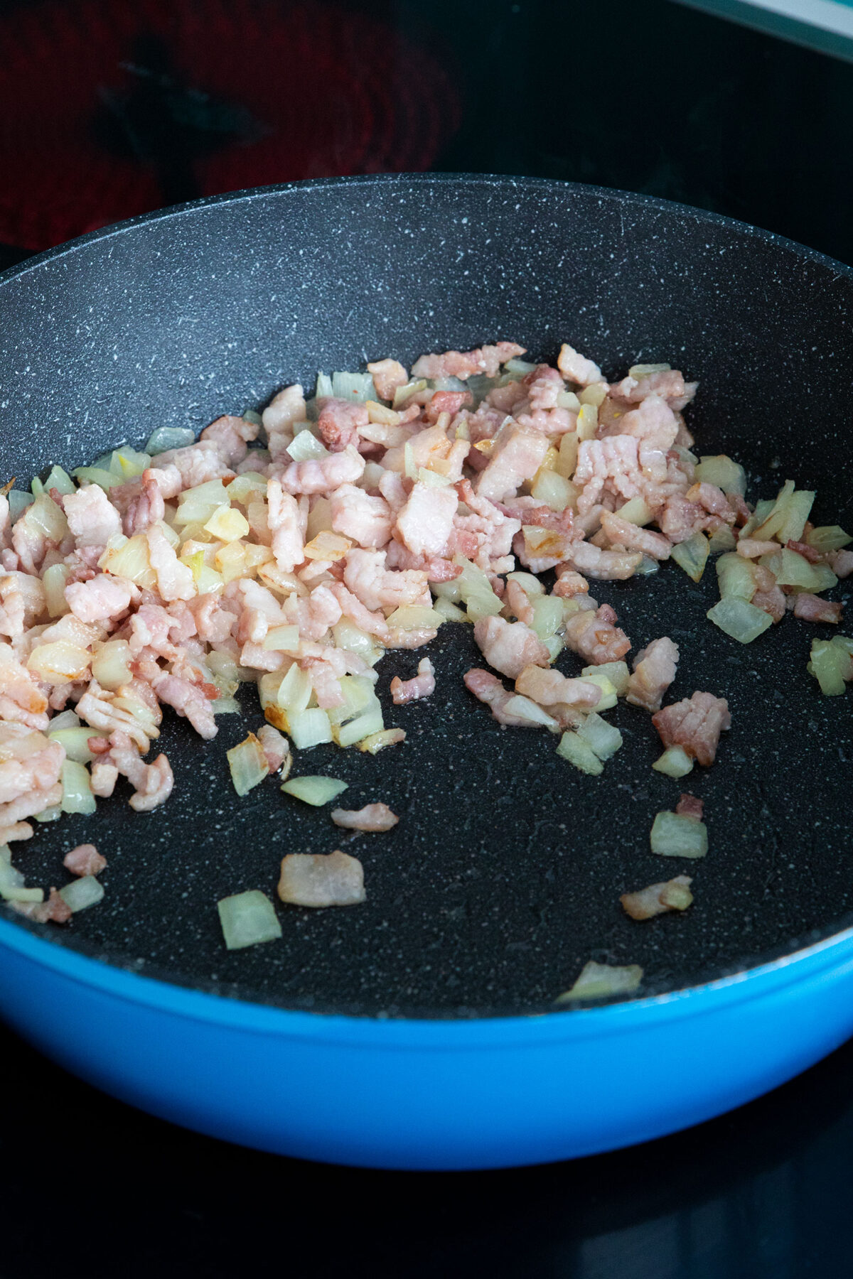 cooking bacon and onions in frying pan