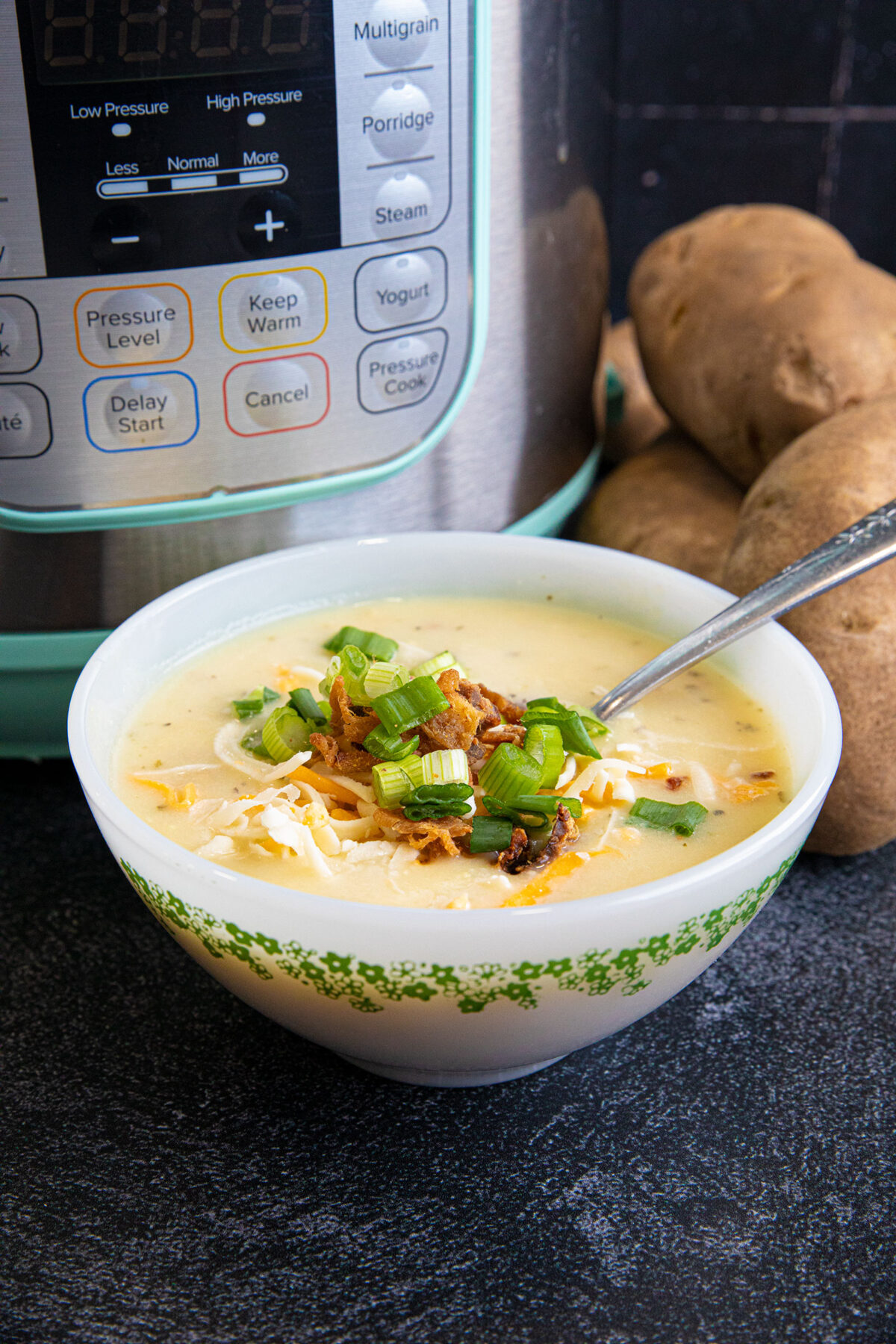 potato soup in a bowl with onions and bacon with an instant pot in the background