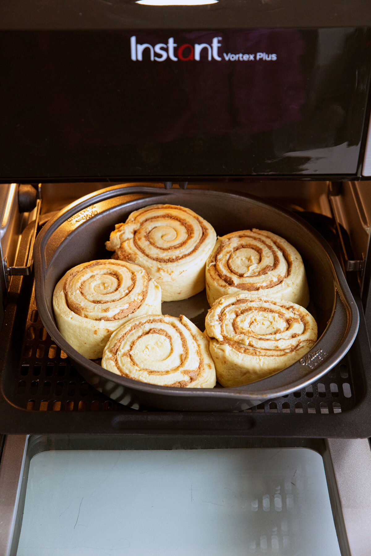 cinnamon roll dough in a baking pan in an air fryer 