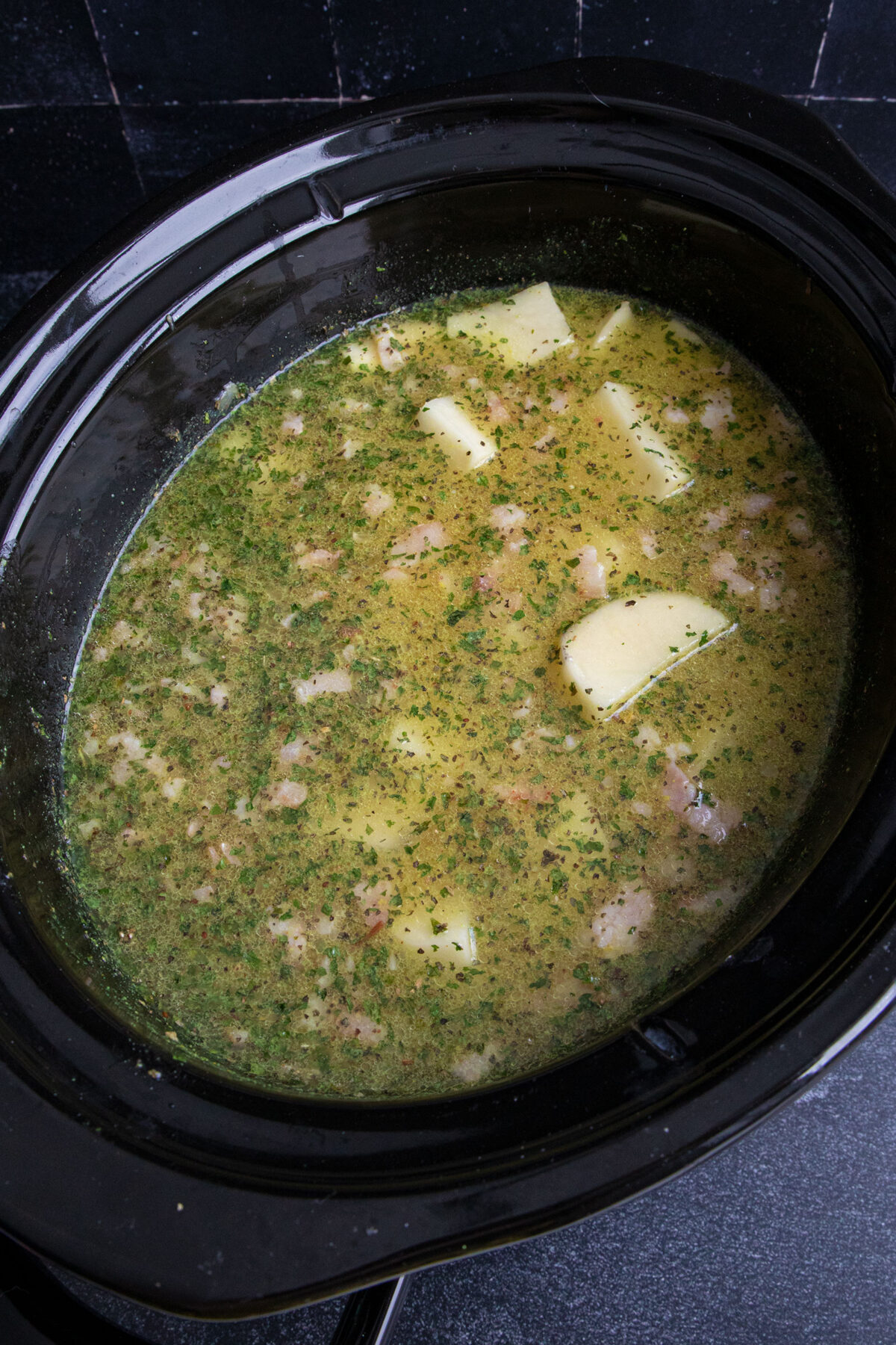 potatoes, spices, bacon and broth in a slow cooker ready to cook