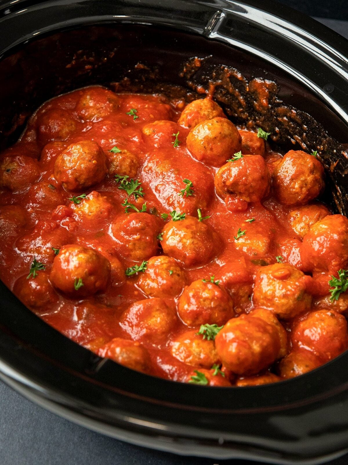 Frozen meatballs cooked in pasta sauce in the slow cooker